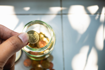 Closeup hand put coin into bottle using as money saving and business concept