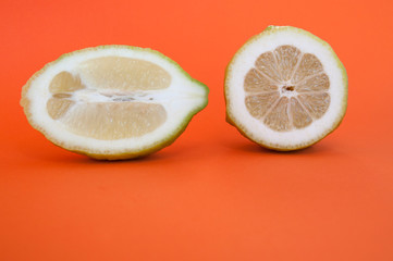 two halves of lemon cut in half and across on orange background side view
