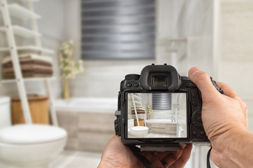 Hands holding DSLR capturing interior of a modern bathroom