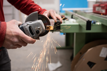 worker cutting an aluminium piece with a grinder	