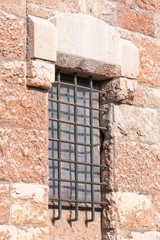 Old window with a rusty steel grate in a historic building