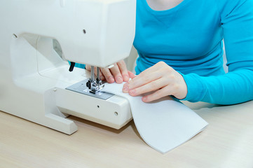 Caucasian girl sews a felt cloth on a sewing machine. Close-up.