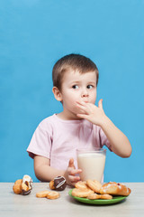 Cute little boy drinking milk on blue background.