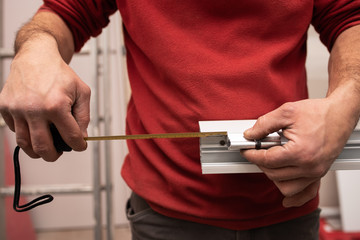 close up of worker hands taking measurements with a tape measure of an aluminium door