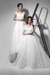 Fototapeta na wymiar Two beautiful slim young brides wearing wedding white dress. Studio shot