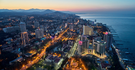 Top view of the evening city of Sochi with lights, modern houses and the sea. Aerial view