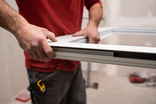 close up of worker assembling an aluminium door in workshop