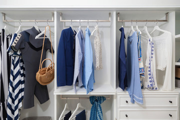 beach blue clothes and windsurf suit hanging in white wardrobe at home