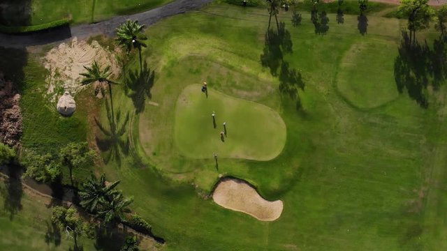 Golfers walking on green with putter - Aerial top view photo from flying drone 