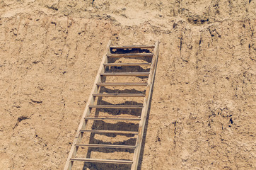 Wooden staircase attached to a clay rock on a sunny day