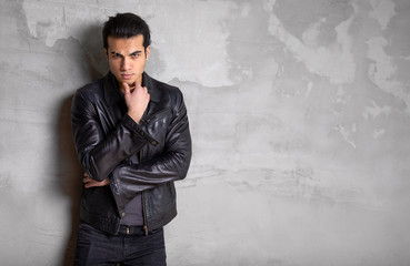 portrait of a young man with serious intentions. Dark grey cement background with a resolute pose....