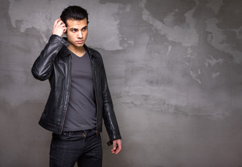 portrait of man on a cement wall background. A young man in a black leather jacket. Free space for...