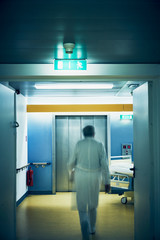 Fototapeta na wymiar Arzt läuft im Flur einer Klinik auf den Aufzug zu