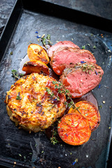 Traditioneller Hirschrücken mit schweizer Rösti, Quitte und Orangen Scheiben in Wild Rotwein...