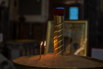 Candles in Russian orthodox cathedral with icons on background