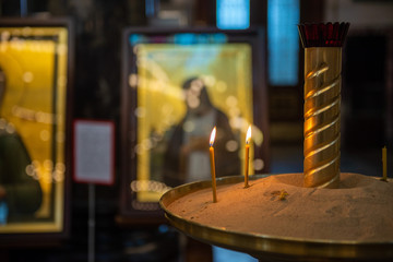 Candles in Russian orthodox cathedral with icons on background