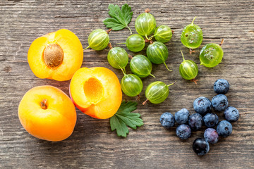 Vegetarian Summer breakfast berries still life in flat lay.  Apricots, goosberries and blueberries on a rustic wooden background.