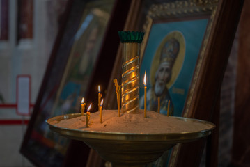 Candles in Russian orthodox cathedral with icons on background