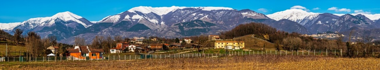 wide winter panorama of rural houses under Italian Marsicani mountain range