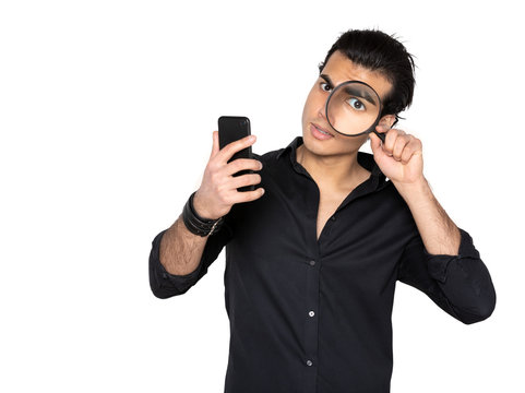 the man examines a mobile phone with a magnifying glass. Man in black shirt on isolated background