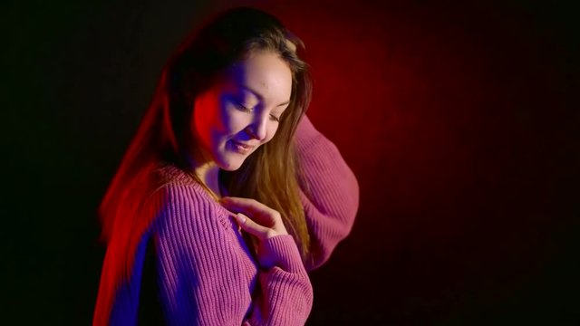 Attractive sensual woman in a pink sweater posing inside a studio.