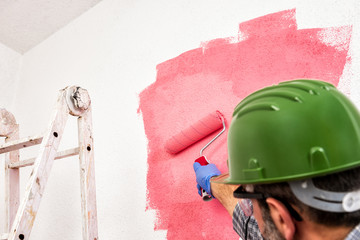 Professional house painter at work painting the wall © francescomou