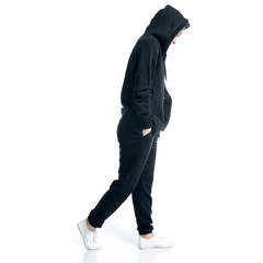 Woman in black tracksuit hood walking goes on white background isolation, back view