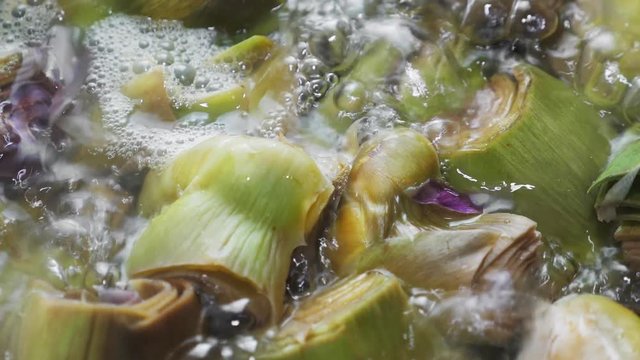 Boiling and cooking artichokes in saucepan, closeup