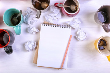 Empty dirty coffee cups, different colors on the table and a notebook for writing a letter. Concept...