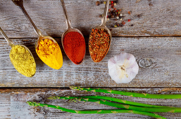 various ground spices in spoons on old wooden table, top view