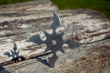 Shuriken (throwing star), traditional japanese ninja cold weapon stuck in wooden background