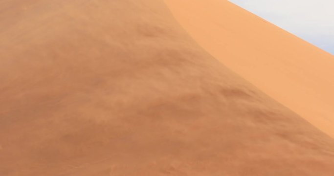 Red orange sand dune wave patterns with wind blowing sand over the dune, Sossusvlei, Namibia. Strong wind in the sand desert, pour. Landscape in Africa.