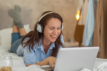 Mature brunette woman using laptop in bedroom