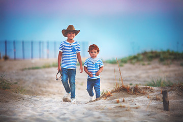 two cute brothers, friends walking through the sandy desert field, playing cowboys, summer adventure