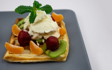 Waffles with ice cream, strawberries, mint, kiwi, mendarine, background, copyspace