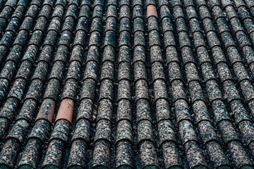Perspective view of the tile roof with patchy tiles and several tiles of solid clay color; an old roof in Portugal covered with clay tiles overlapping each other