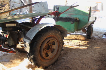 Obraz premium Garden walk-behind tractor on off-road wheels with a trailer in the backyard - farming, cottage, winter