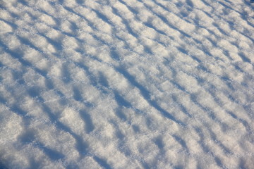 Diagonal wavy texture of the snow dune under the sun - winter background