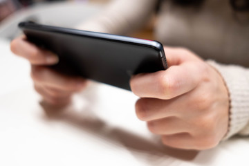 Young female hans with black smarphone watching screen. Digital device addiction, social and education.