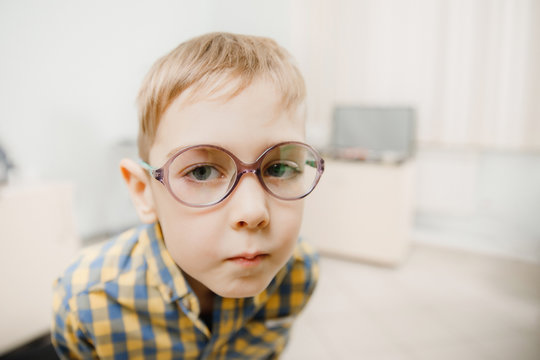 Child boy squints in glasses for eyes of sight