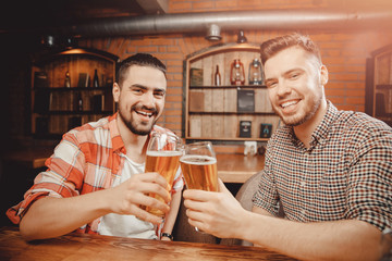 Meet cheerful friends at bar, drink draft beer in mugs and chat