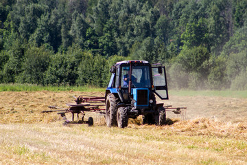 Fototapeta premium Tractor removes the straw after the grain harvest