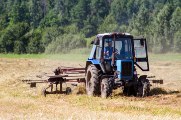 Obraz premium Tractor removes the straw after the grain harvest