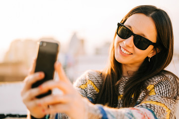 Happy young woman with sunglasses taking selfie on a terrace in New York