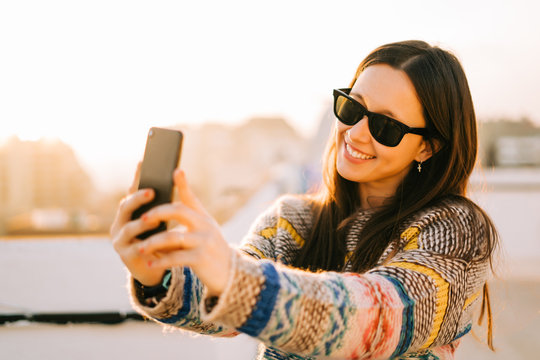 Happy young woman with sunglasses taking selfie on a terrace in New York