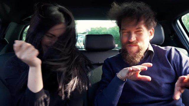 Happy man and woman shaking long hair dancing in car slow motion