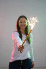 Pretty smiling young woman holding big and colorful sparkler