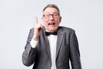 Happy senior man showing index fingers up, giving advice or recommendation