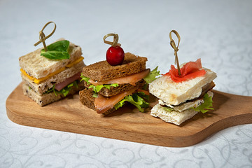 Buffet sandwiches with fish, cheese and cucumbers on the kitchen board. Restaurant menu.