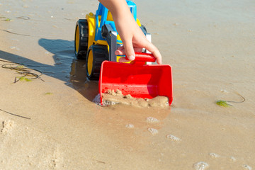 Children's toy tractor on the sand at sea.